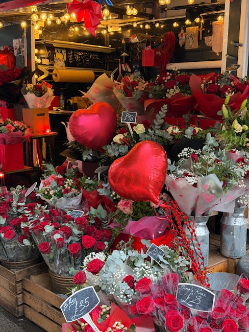 A vibrant display of floral arrangements at South Hackney flowers, featuring red and white flowers including roses, carnations, and lilies, complemented by greenery and decorative elements such as hea